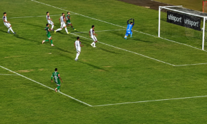 Jogadores do Uberlândia avançam em direção ao gol durante partida contra o Betim, enquanto goleiro acompanha a jogada dentro da área